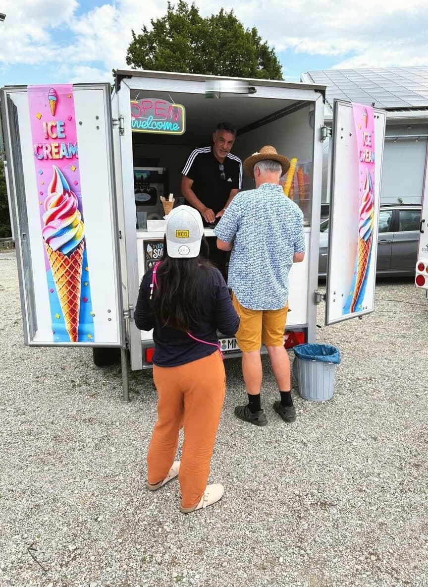 Gäste werden am geöffneten Softeis-Anhänger von Mondy Softeis bedient